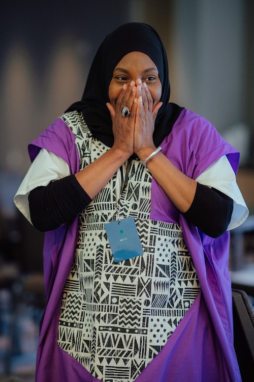 A photo of Rashida James-Saadiya, director of the Muslim Power Building Project, covering her mouth with her hands in delight